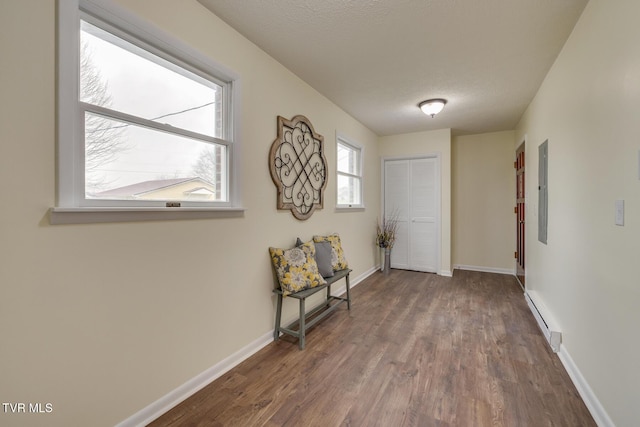 hallway with wood-type flooring, a textured ceiling, and a baseboard heating unit