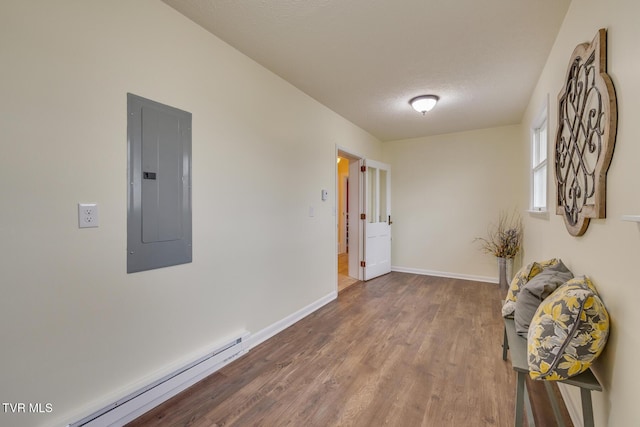 corridor with hardwood / wood-style floors, baseboard heating, electric panel, and a textured ceiling