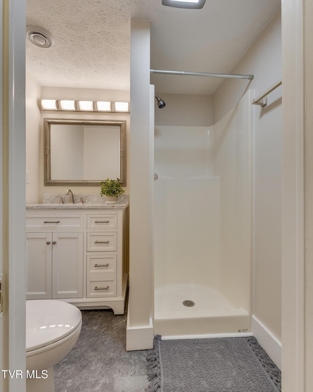 bathroom with vanity, a shower, a textured ceiling, and toilet