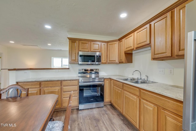 kitchen with sink, light stone counters, light hardwood / wood-style flooring, appliances with stainless steel finishes, and ornamental molding