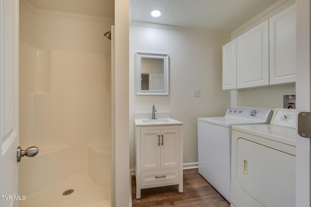 laundry area featuring cabinets, dark hardwood / wood-style flooring, ornamental molding, sink, and washer and dryer