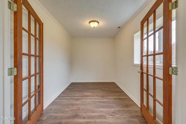 spare room with french doors, dark hardwood / wood-style flooring, a textured ceiling, and ornamental molding