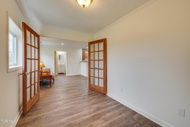 unfurnished room with hardwood / wood-style floors, ornamental molding, a textured ceiling, and french doors