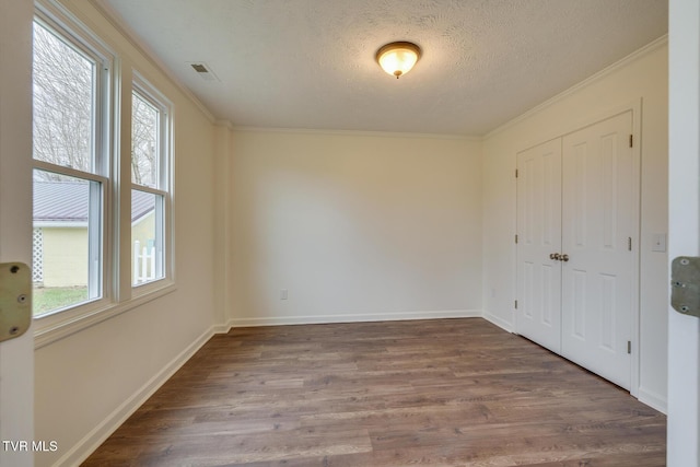 interior space with a wealth of natural light, crown molding, dark wood-type flooring, and a textured ceiling