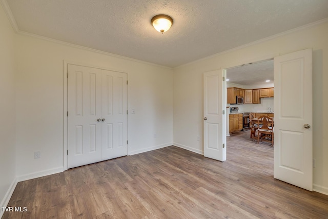 spare room with a textured ceiling, light hardwood / wood-style flooring, and ornamental molding