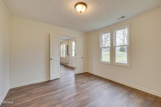 empty room featuring crown molding, dark hardwood / wood-style flooring, and a textured ceiling