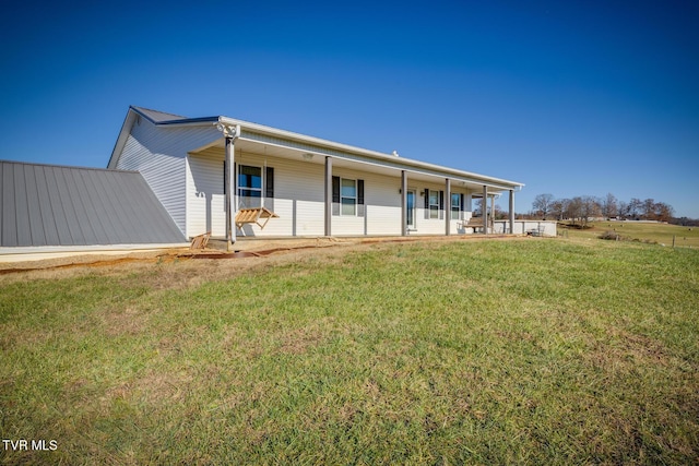 rear view of property with covered porch and a lawn