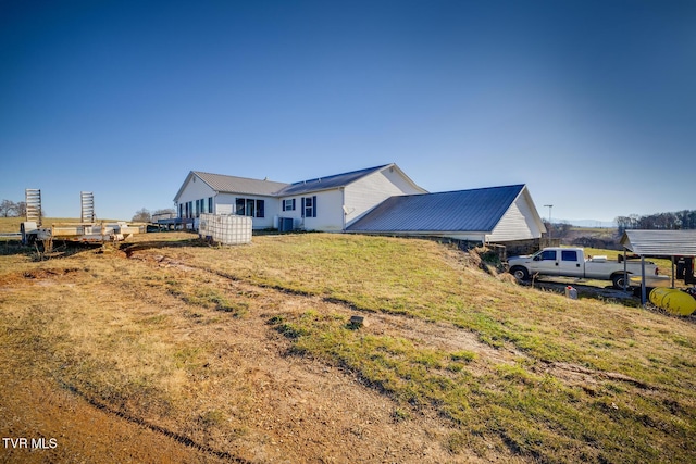 back of house with central air condition unit and a yard