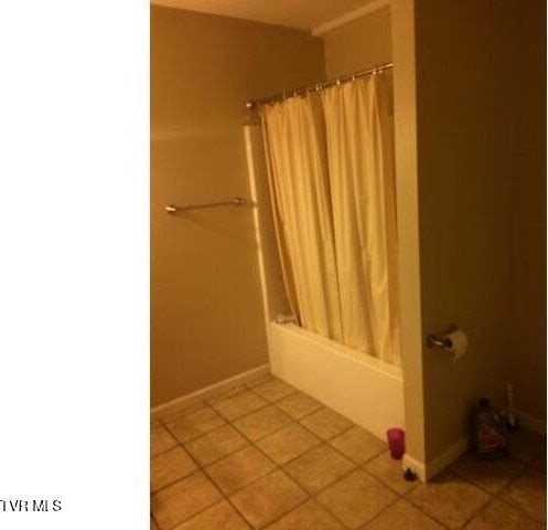 bathroom with shower / bath combo and tile patterned floors