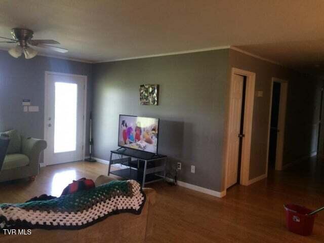 living room featuring hardwood / wood-style flooring, ceiling fan, and ornamental molding