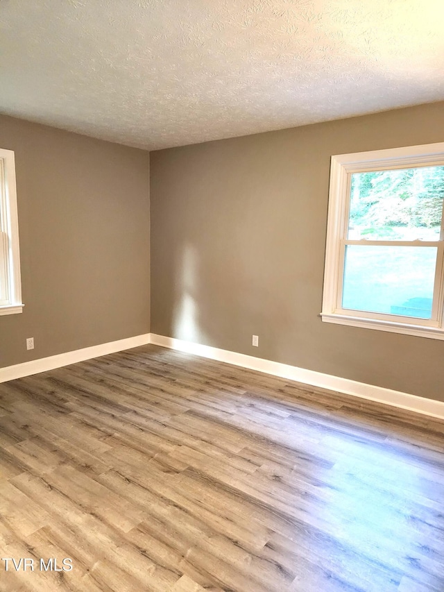 unfurnished room with light hardwood / wood-style flooring and a textured ceiling