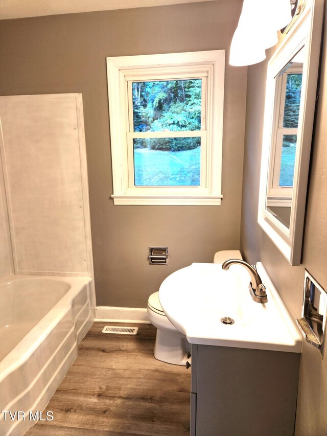 bathroom featuring vanity, toilet, wood-type flooring, and a tub