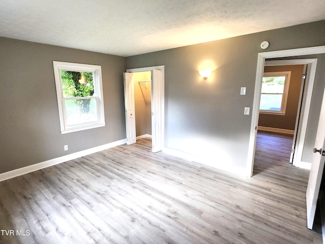 unfurnished room featuring a textured ceiling and light hardwood / wood-style flooring