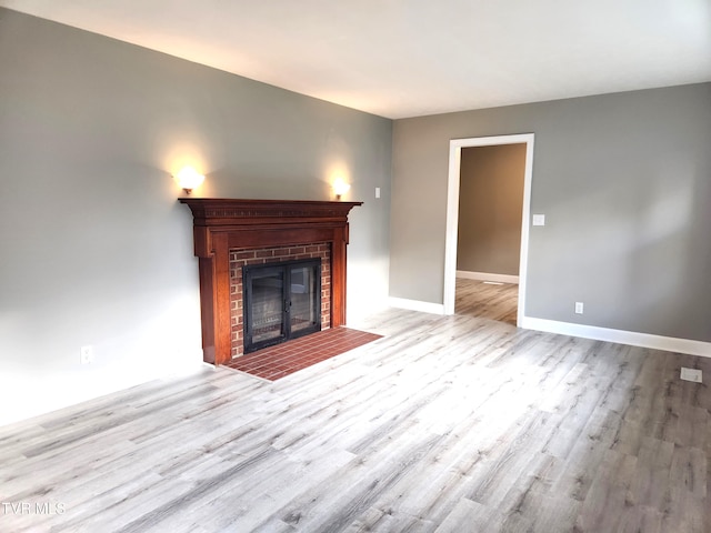 unfurnished living room featuring a brick fireplace and light wood-type flooring