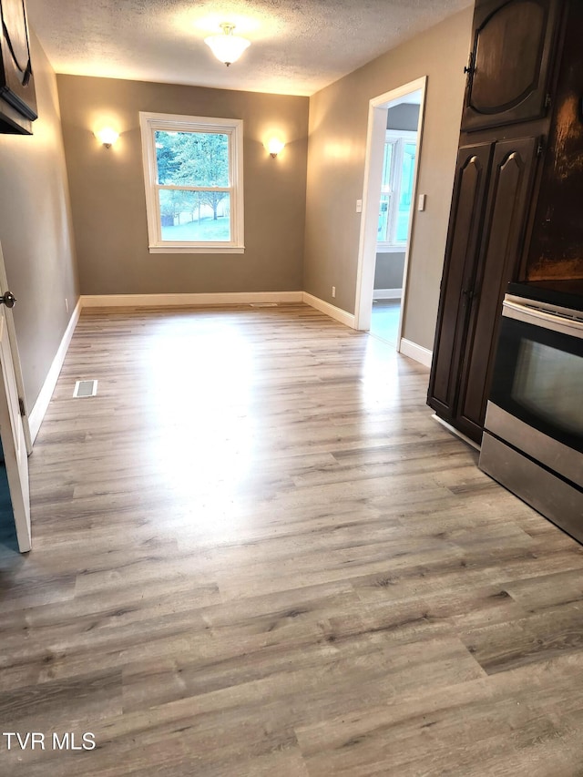 spare room with light wood-type flooring and a textured ceiling