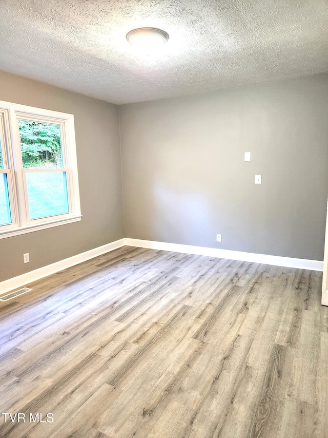 spare room featuring a textured ceiling and light wood-type flooring