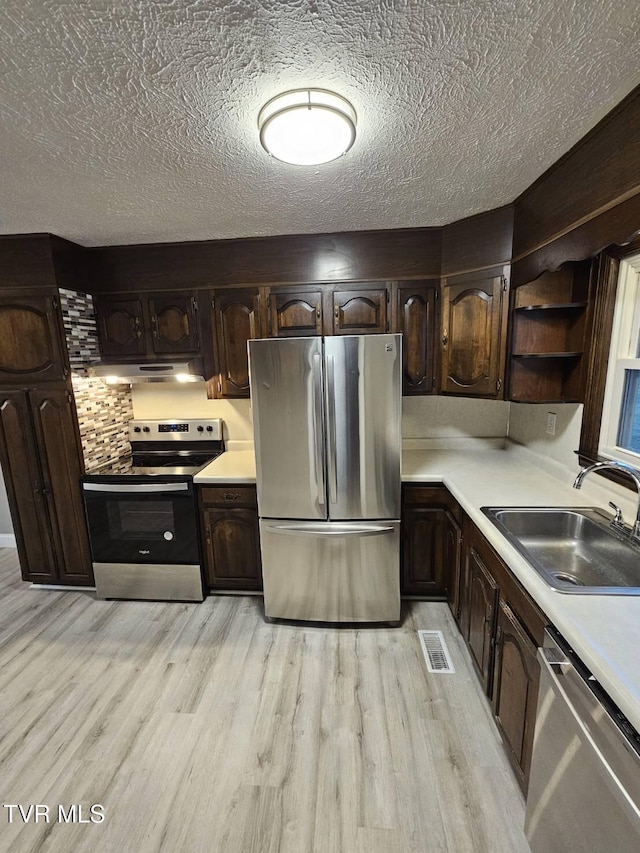 kitchen featuring sink, dark brown cabinets, stainless steel appliances, and light hardwood / wood-style floors