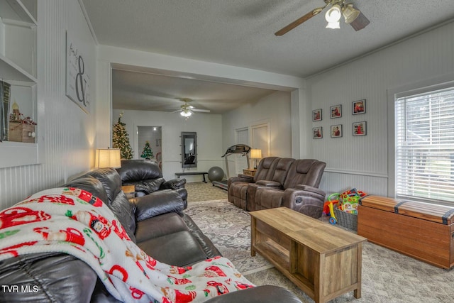 carpeted living room featuring ceiling fan and a textured ceiling