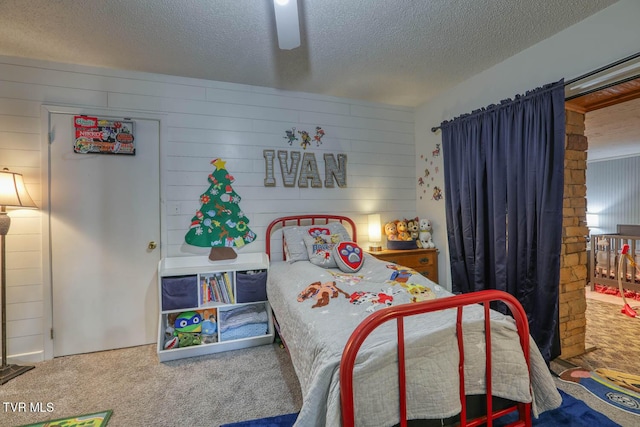 bedroom featuring carpet flooring, ceiling fan, wood walls, and a textured ceiling