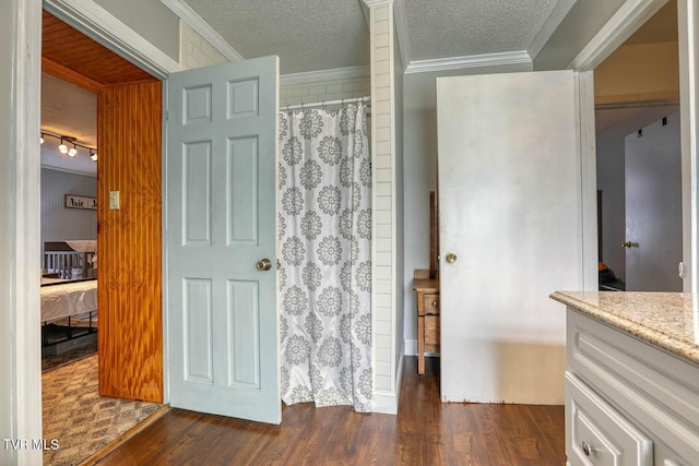 bathroom featuring curtained shower, a textured ceiling, hardwood / wood-style flooring, vanity, and ornamental molding