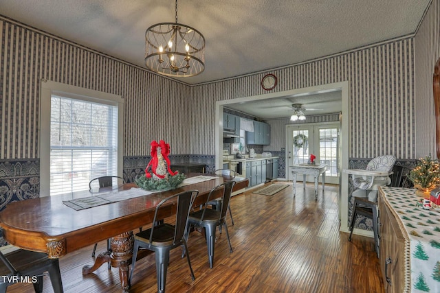 dining space with ceiling fan with notable chandelier, dark hardwood / wood-style flooring, and a textured ceiling