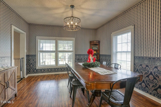 dining space featuring crown molding, dark wood-type flooring, a textured ceiling, and an inviting chandelier