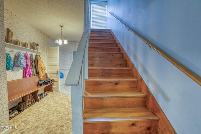 stairway with carpet, a textured ceiling, and a chandelier