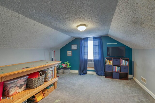 rec room with carpet floors, a textured ceiling, and vaulted ceiling