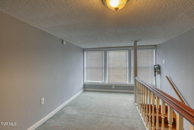 carpeted empty room with a textured ceiling