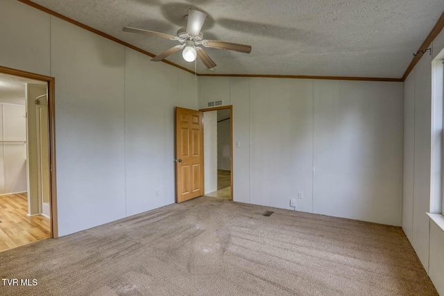 carpeted spare room with ceiling fan, lofted ceiling, a textured ceiling, and ornamental molding