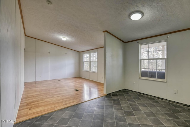 unfurnished room with a textured ceiling, dark hardwood / wood-style floors, a wealth of natural light, and crown molding