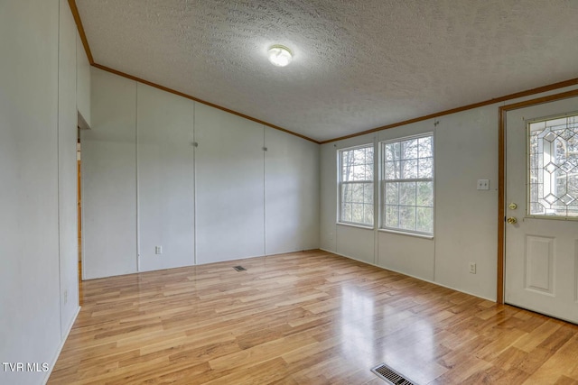 entryway with a wealth of natural light, a textured ceiling, and light wood-type flooring