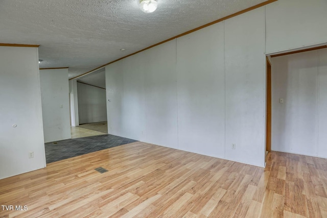 unfurnished room with light hardwood / wood-style floors, ornamental molding, and a textured ceiling