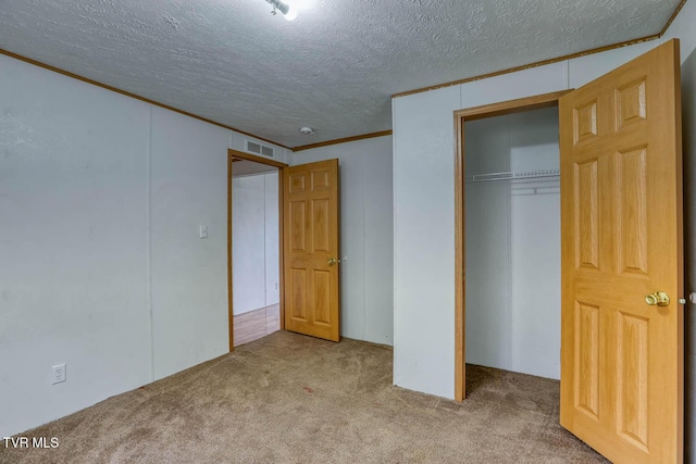 unfurnished bedroom with crown molding, light colored carpet, a textured ceiling, and a closet