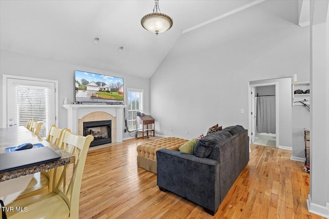 living room with high vaulted ceiling, wood-type flooring, and ornamental molding