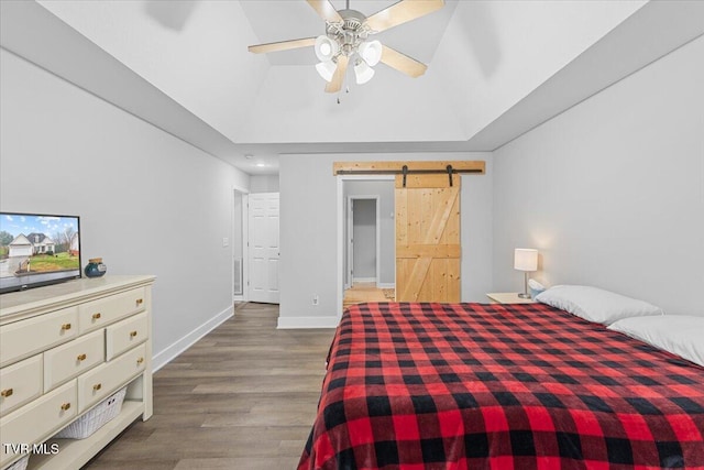 bedroom with hardwood / wood-style flooring, ceiling fan, a barn door, and lofted ceiling