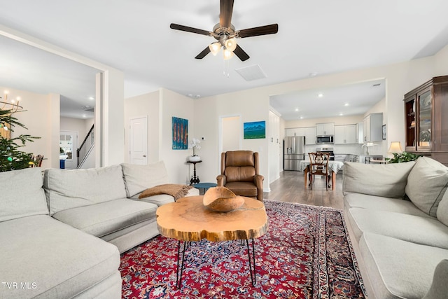 living room featuring ceiling fan with notable chandelier and hardwood / wood-style flooring