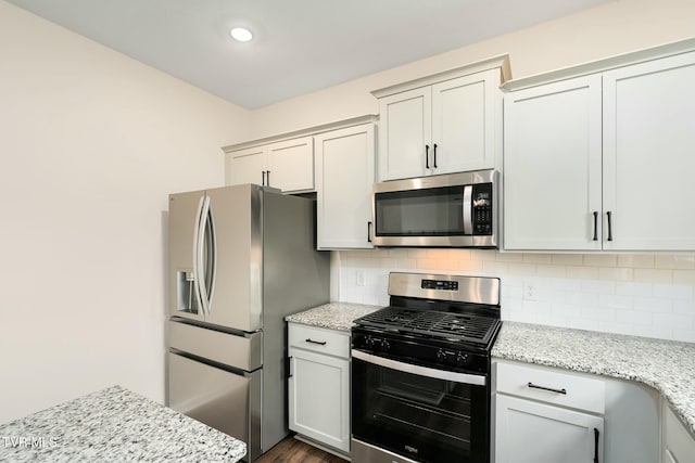 kitchen with appliances with stainless steel finishes, tasteful backsplash, and light stone counters