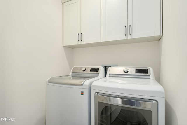 clothes washing area with cabinets and washer and clothes dryer