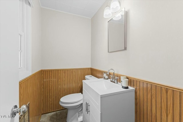 bathroom featuring wooden walls, tile patterned flooring, vanity, and toilet