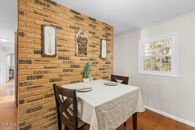 dining space featuring hardwood / wood-style floors and brick wall