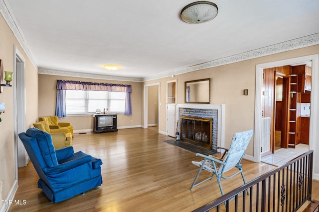 living room featuring a fireplace, crown molding, and hardwood / wood-style floors