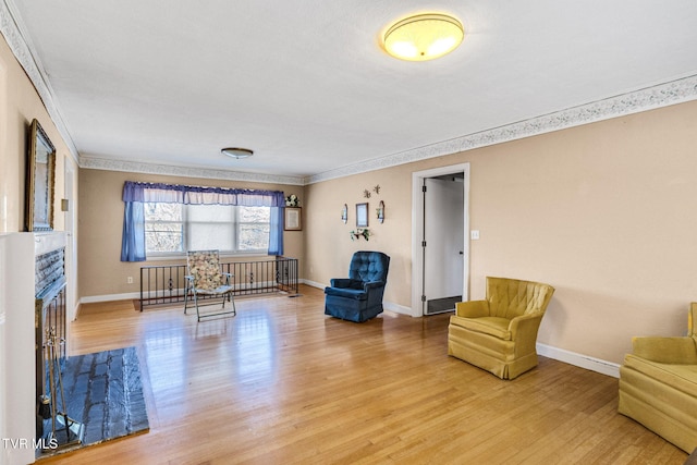 sitting room featuring hardwood / wood-style floors, a stone fireplace, and ornamental molding