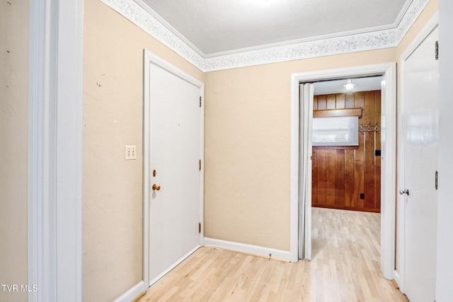 hall featuring light hardwood / wood-style floors, a textured ceiling, and ornamental molding