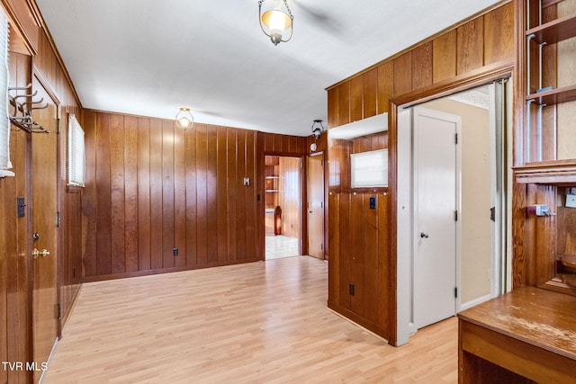 spare room featuring light hardwood / wood-style floors and wooden walls