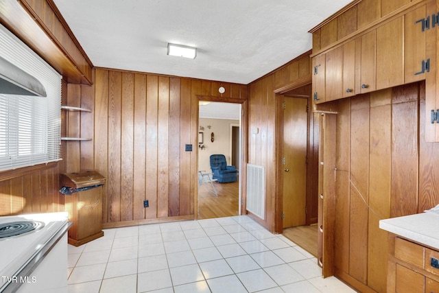 kitchen featuring wooden walls, crown molding, and light tile patterned flooring