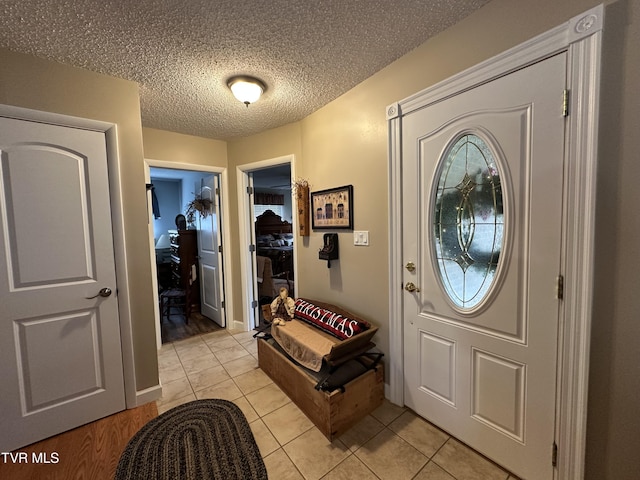 entryway with a textured ceiling and light tile patterned flooring