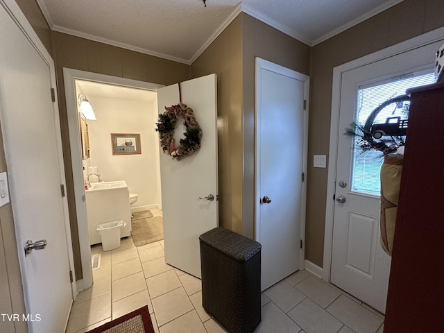 tiled foyer entrance with a textured ceiling and ornamental molding