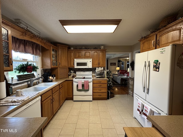 kitchen with white appliances, sink, light tile patterned floors, a textured ceiling, and tasteful backsplash