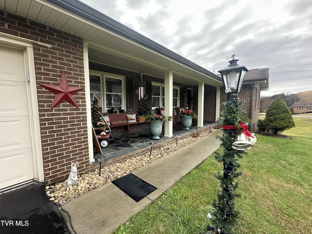 view of exterior entry featuring a yard and covered porch